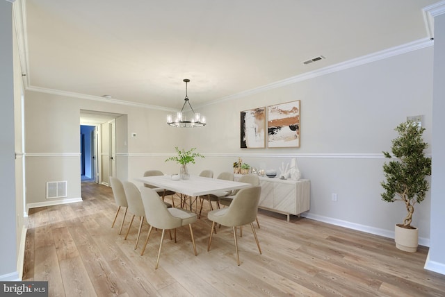 dining area featuring ornamental molding, light hardwood / wood-style flooring, and a chandelier