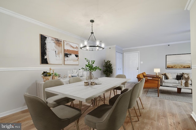 dining room featuring ornamental molding, light wood-type flooring, and a chandelier