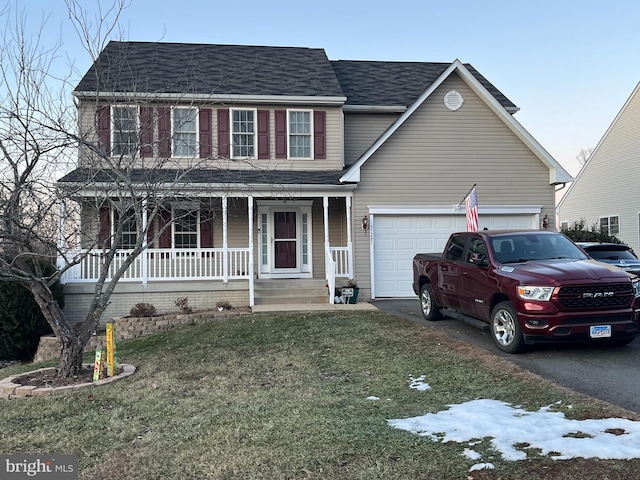 view of front of property featuring a porch, a garage, and a yard