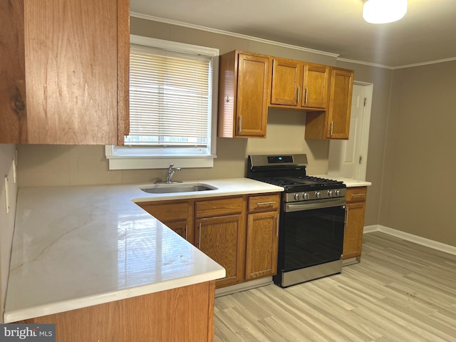 kitchen featuring gas stove, light hardwood / wood-style floors, crown molding, and sink