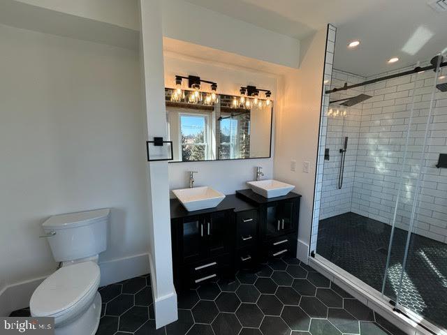 full bath with toilet, tile patterned flooring, a sink, and a shower stall