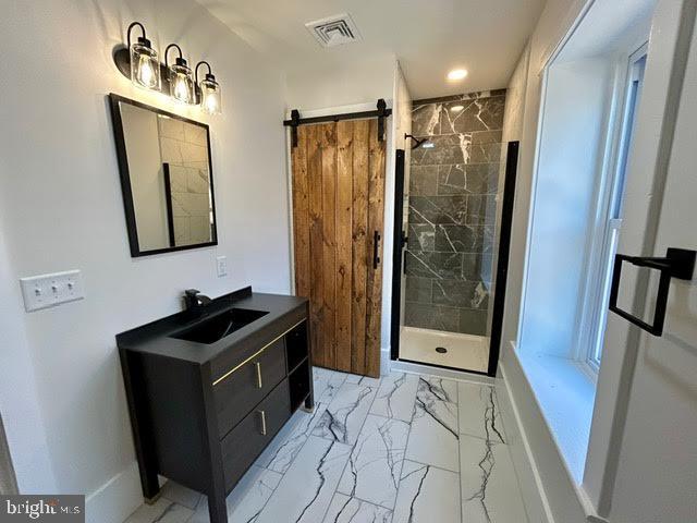 bathroom featuring marble finish floor, visible vents, a stall shower, vanity, and baseboards