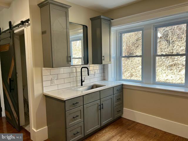 bathroom with baseboards, decorative backsplash, wood finished floors, and vanity