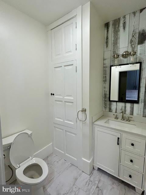 bathroom with toilet, marble finish floor, baseboards, and vanity