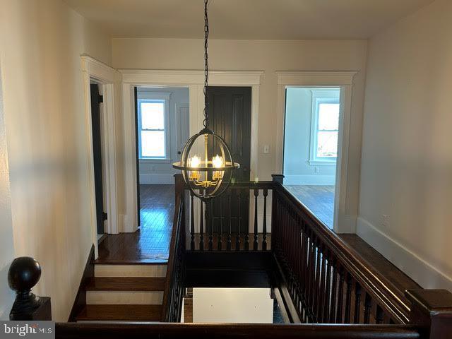 staircase featuring wood finished floors, a healthy amount of sunlight, and an inviting chandelier