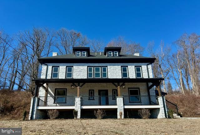 traditional style home with covered porch, stone siding, and a chimney