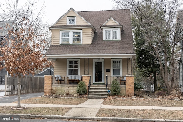 view of front of property with a porch, fence, and a shingled roof