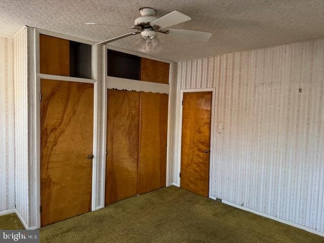 unfurnished bedroom featuring a textured ceiling, ceiling fan, and dark colored carpet