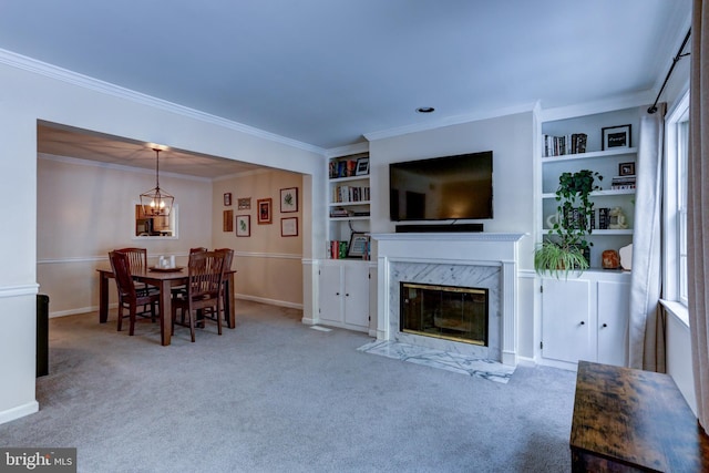 living room with a notable chandelier, a high end fireplace, built in features, ornamental molding, and light carpet