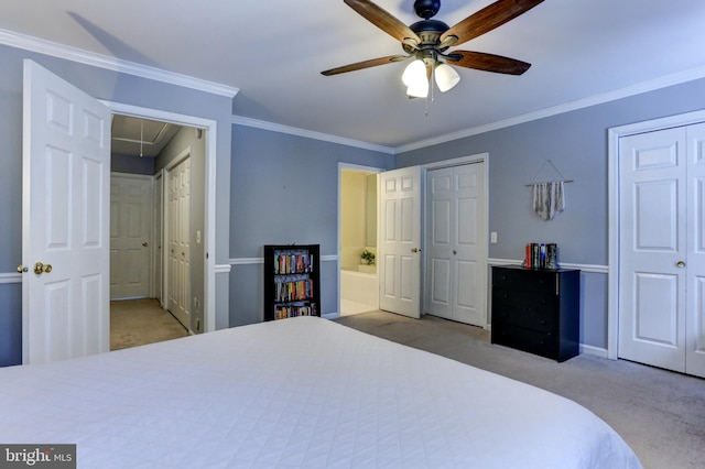 bedroom featuring ensuite bath, light colored carpet, crown molding, ceiling fan, and two closets