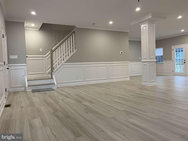 unfurnished living room featuring decorative columns, crown molding, and light wood-type flooring