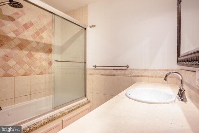 bathroom with sink, enclosed tub / shower combo, and tile walls