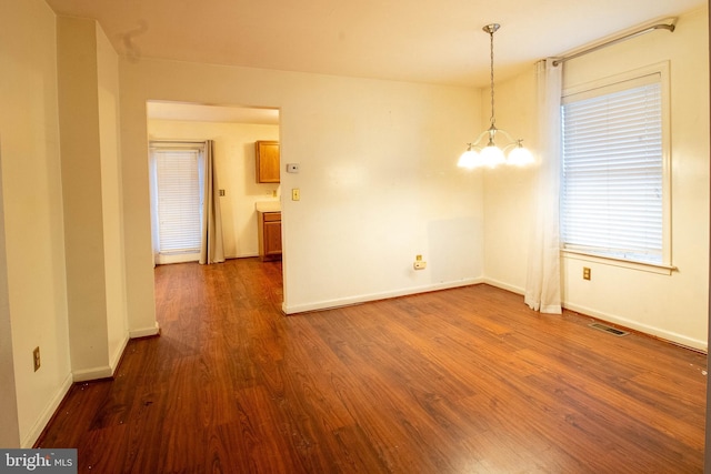 spare room with dark hardwood / wood-style flooring and a notable chandelier