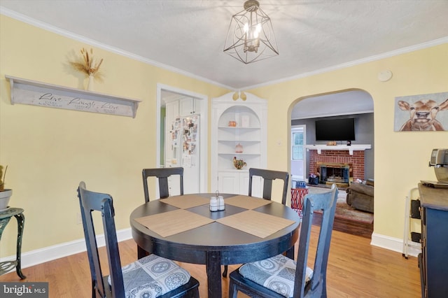 dining space with crown molding, a fireplace, hardwood / wood-style floors, and a textured ceiling