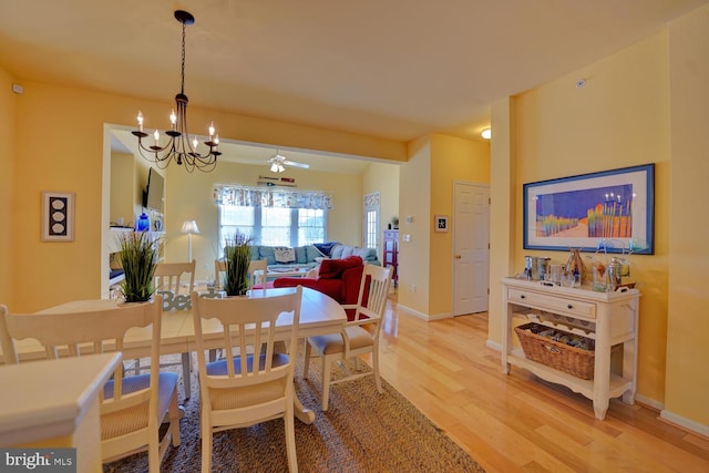 dining room featuring lofted ceiling, wood-type flooring, and ceiling fan with notable chandelier