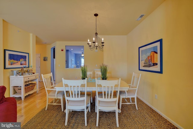 dining area with wood-type flooring and an inviting chandelier