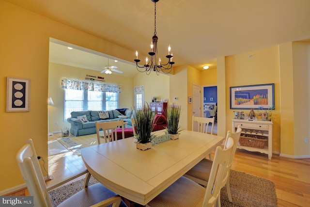 dining space featuring ceiling fan with notable chandelier, light wood-type flooring, and vaulted ceiling