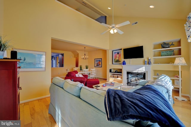 living room with high vaulted ceiling, light hardwood / wood-style floors, and ceiling fan with notable chandelier