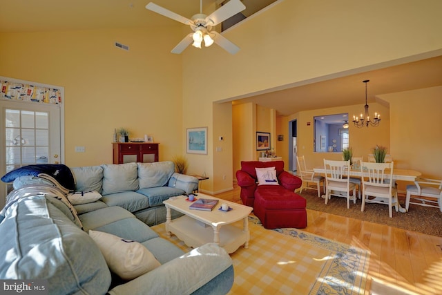 living room featuring high vaulted ceiling, ceiling fan with notable chandelier, and hardwood / wood-style flooring