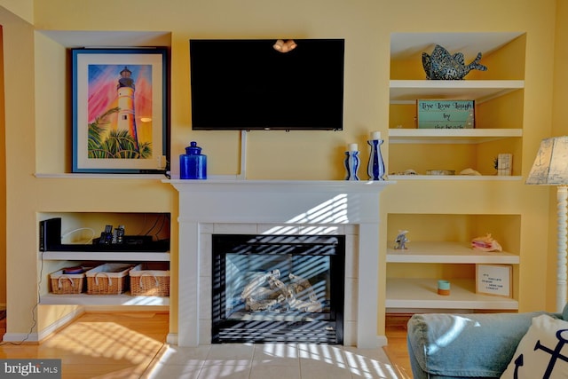 living room with built in features, light tile patterned floors, and a tiled fireplace