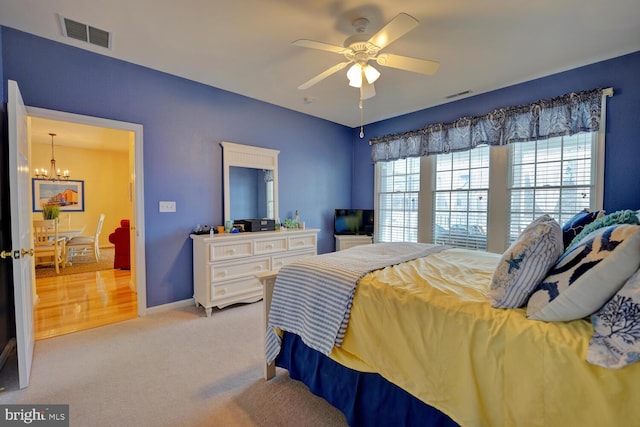 bedroom with light carpet and ceiling fan with notable chandelier