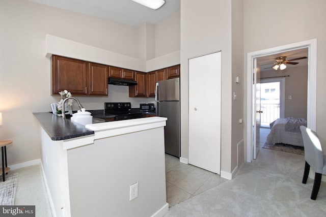 kitchen with sink, a towering ceiling, black appliances, light carpet, and kitchen peninsula