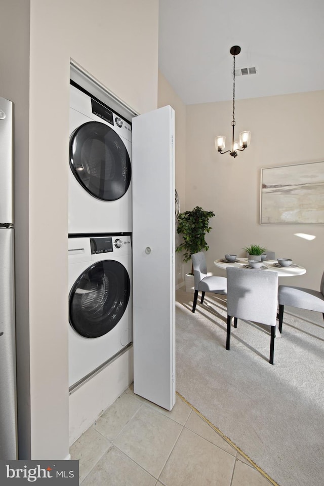 washroom with light colored carpet, stacked washing maching and dryer, and a chandelier