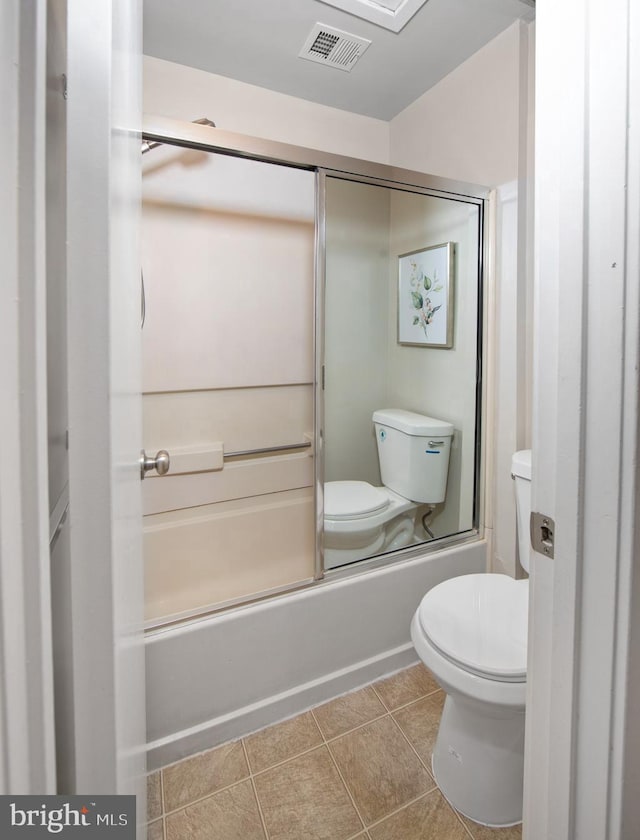 bathroom featuring bath / shower combo with glass door, tile patterned floors, and toilet