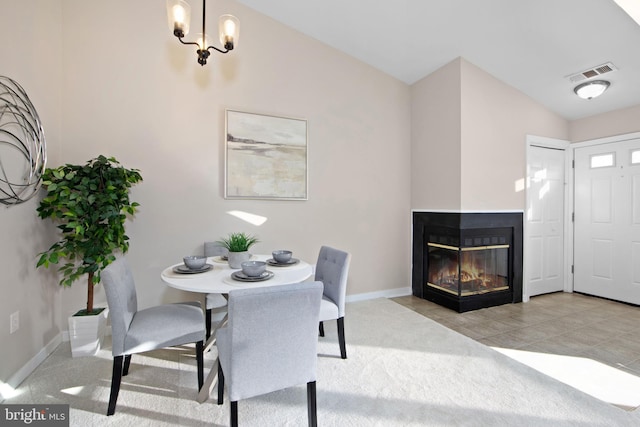 carpeted dining room featuring a multi sided fireplace, vaulted ceiling, and a notable chandelier