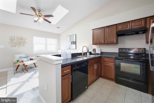 kitchen with light tile patterned flooring, lofted ceiling with skylight, sink, kitchen peninsula, and black appliances