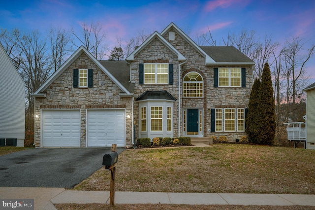 view of front of property featuring aphalt driveway, an attached garage, and central air condition unit