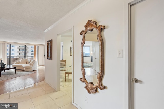 hall with crown molding, light tile patterned flooring, and a textured ceiling