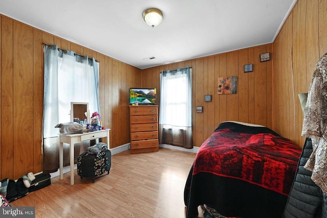 bedroom with wood walls and light hardwood / wood-style floors