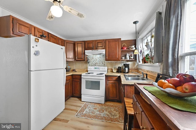 kitchen with white appliances, decorative light fixtures, light wood-type flooring, backsplash, and sink