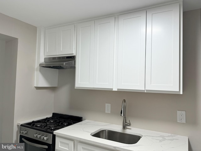 kitchen with white cabinets, light stone counters, gas stove, and sink