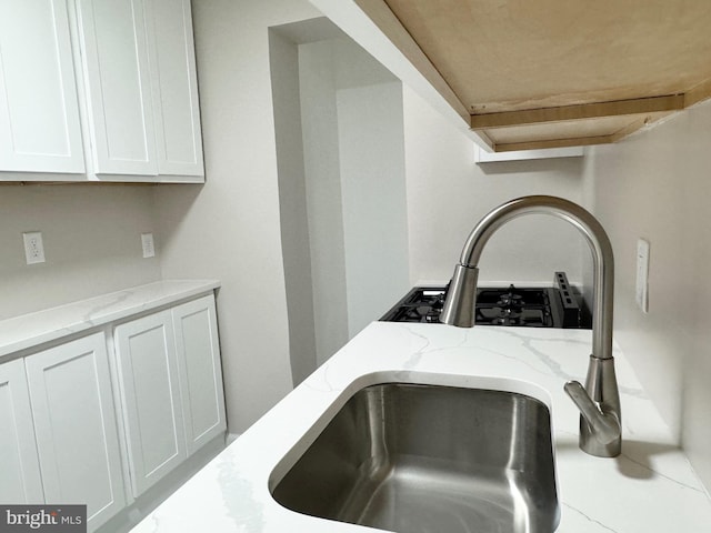 details featuring white cabinetry, light stone counters, and cooktop