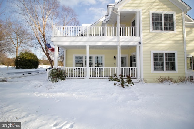 snow covered back of property with a balcony