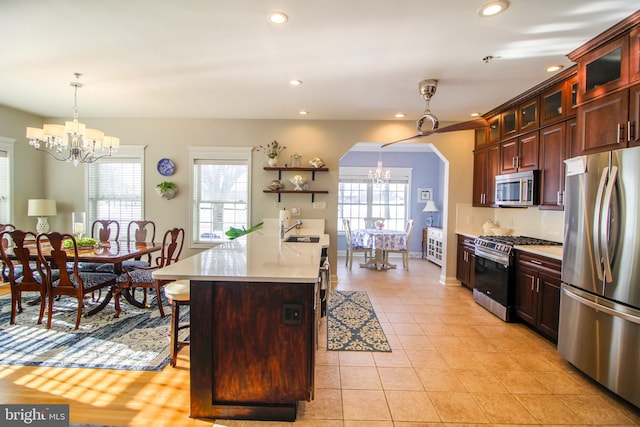 kitchen with light tile patterned flooring, a healthy amount of sunlight, appliances with stainless steel finishes, and an inviting chandelier