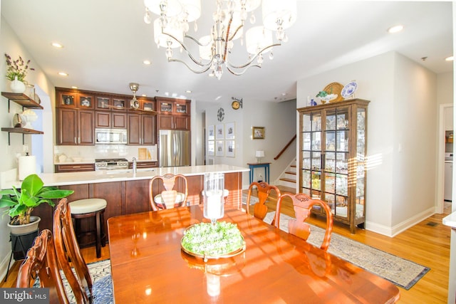 dining area featuring a notable chandelier, sink, and light hardwood / wood-style flooring