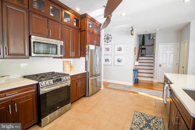 kitchen featuring backsplash, light tile patterned floors, and stainless steel appliances