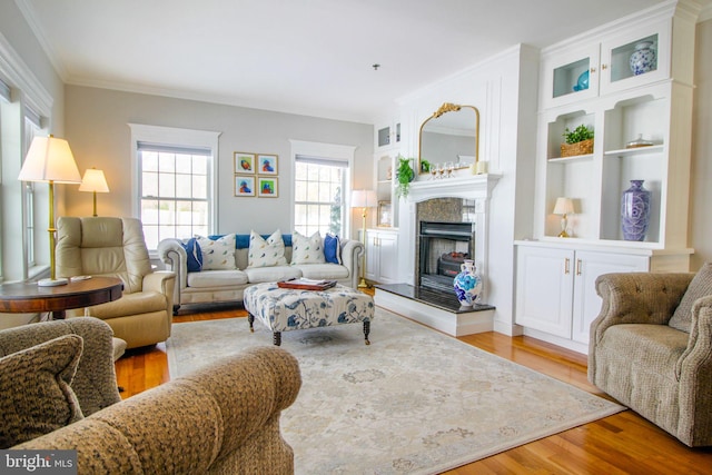 living room with light hardwood / wood-style floors, ornamental molding, and a tiled fireplace