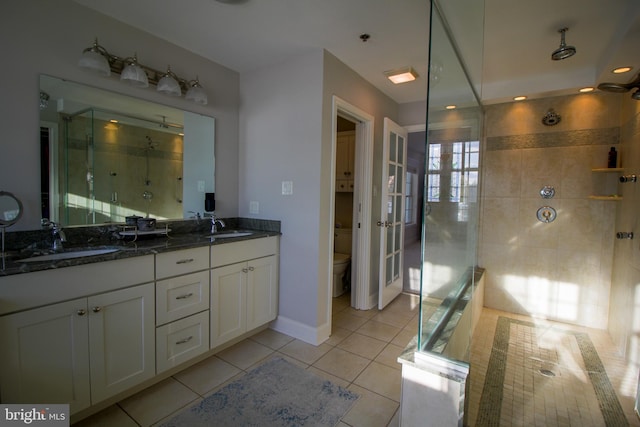 bathroom with tile patterned flooring, vanity, a shower with shower door, and toilet