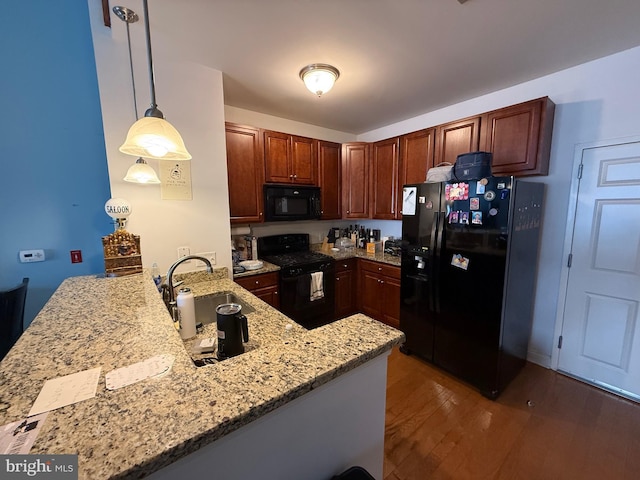 kitchen featuring black appliances, pendant lighting, and kitchen peninsula