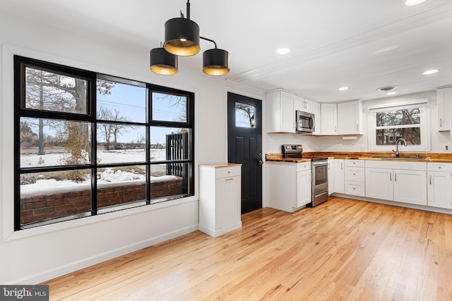 kitchen featuring sink, stainless steel appliances, pendant lighting, and white cabinetry