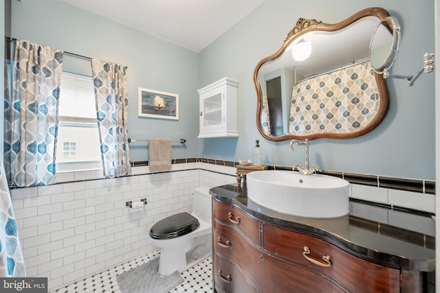 bathroom with tile walls, toilet, vanity, and tile patterned flooring