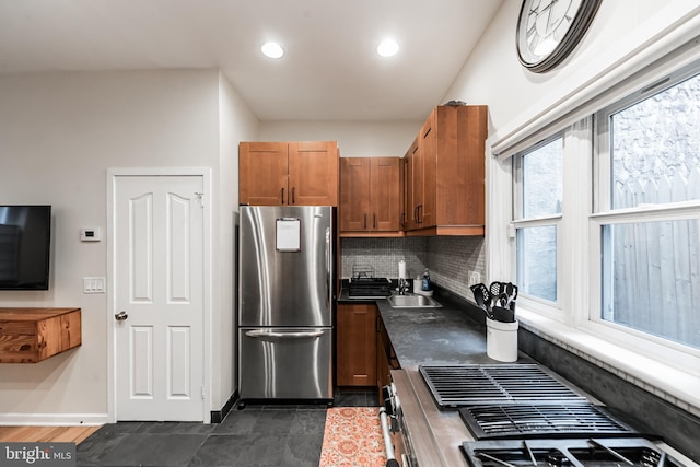 kitchen with stove, sink, tasteful backsplash, and stainless steel refrigerator