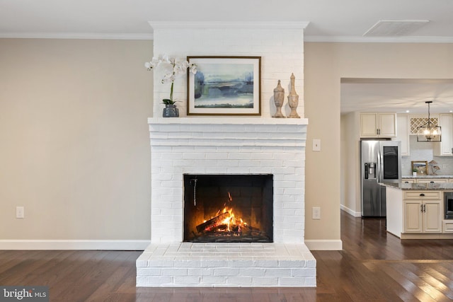 details featuring wood finished floors, crown molding, visible vents, and stainless steel refrigerator with ice dispenser