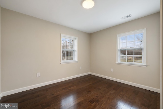 unfurnished room featuring dark wood finished floors, baseboards, and visible vents