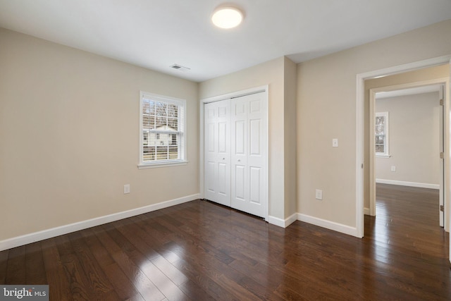 unfurnished bedroom with visible vents, baseboards, and dark wood-style flooring