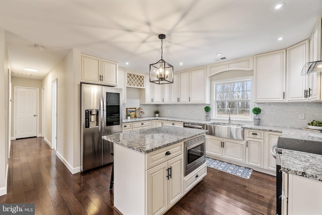 kitchen with dark wood-style floors, stainless steel appliances, light stone counters, and a sink